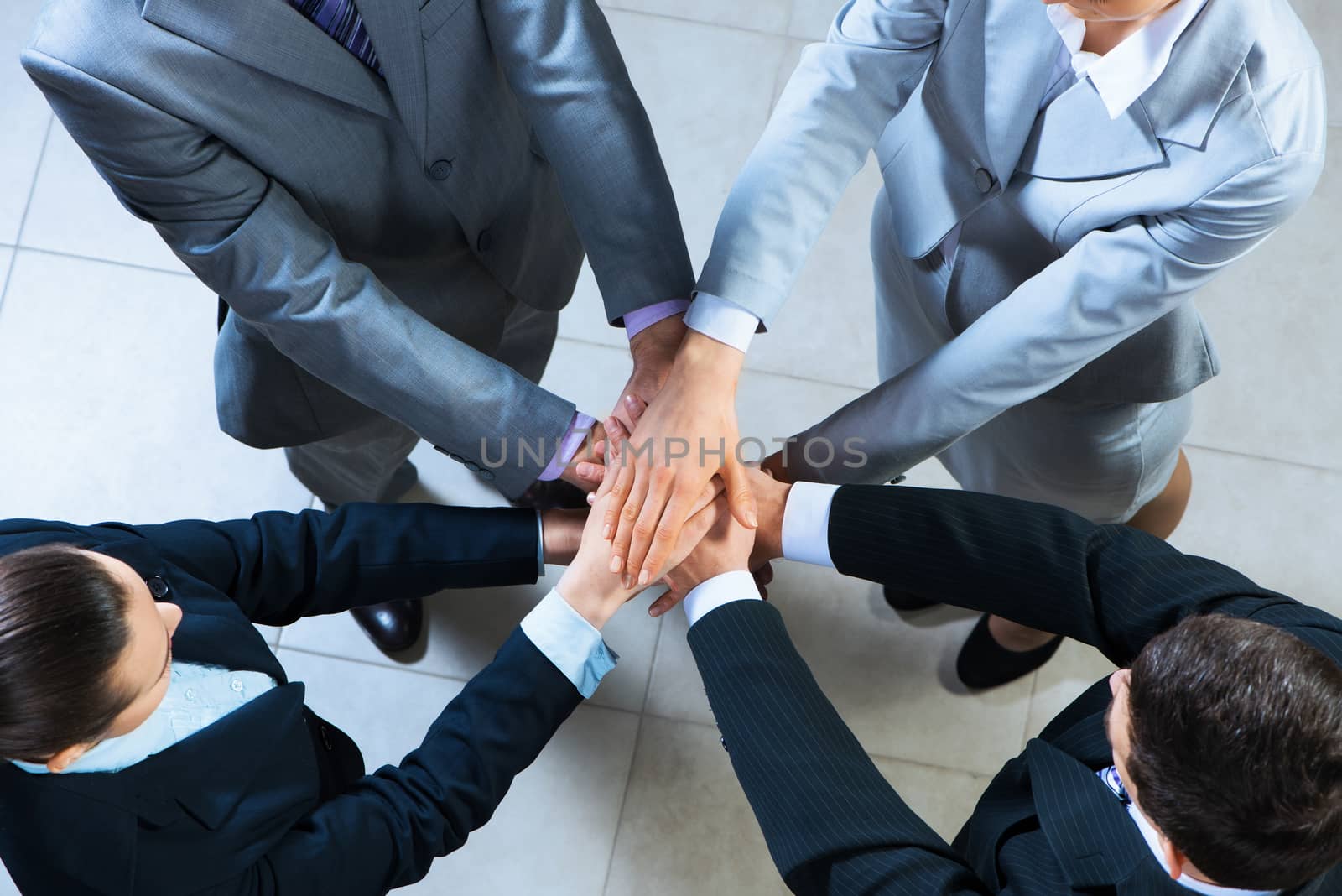 team of four businessmen with folded hands, a symbol of teamwork