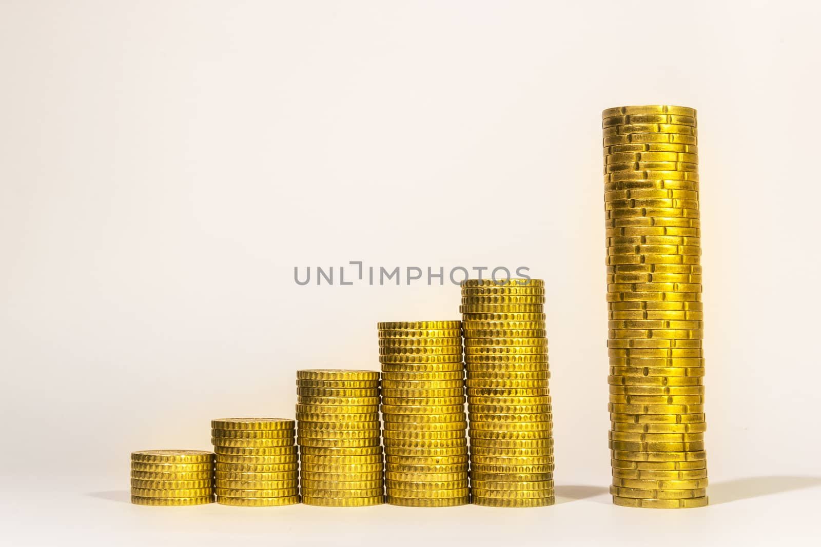 Yellow coins lined up from short to tall stacks with blank background by enrico.lapponi