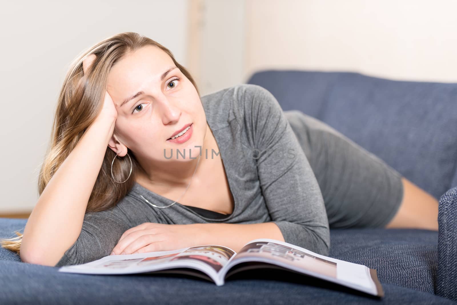 Brunette reading magazine on sofa