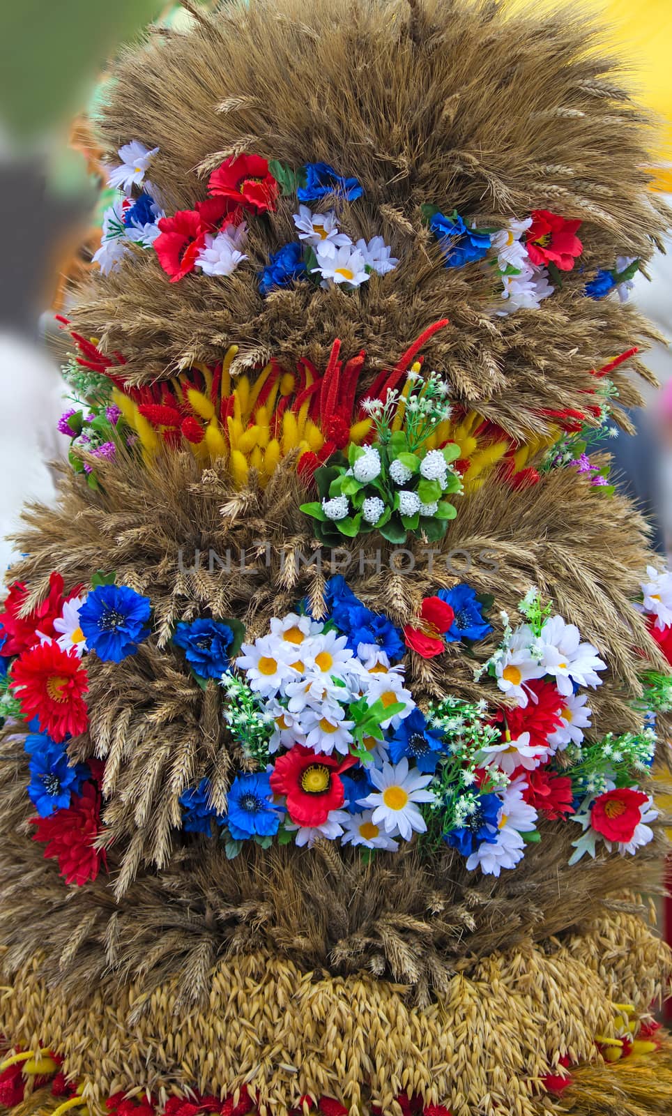 Sheaf beautifully decorated with flowers from stalks of grain cereals.