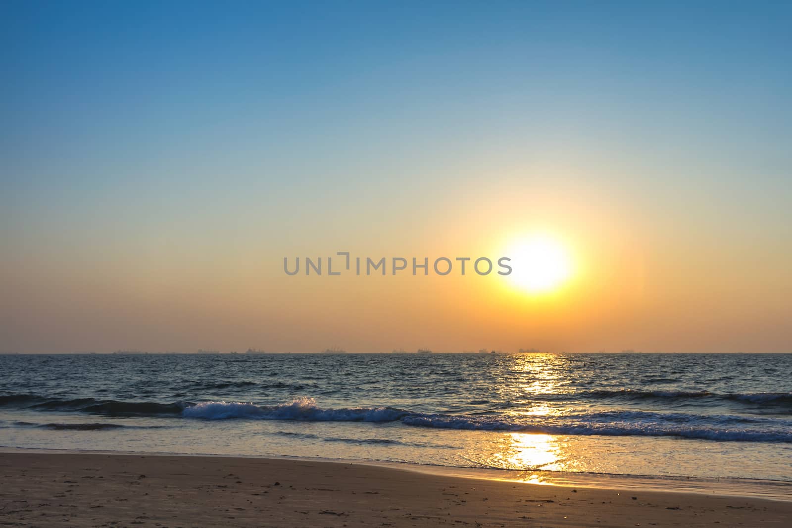 Scenic view from sand beach in Goa to beautiful sunset above the Arabian sea. Sun reflection on sea surface