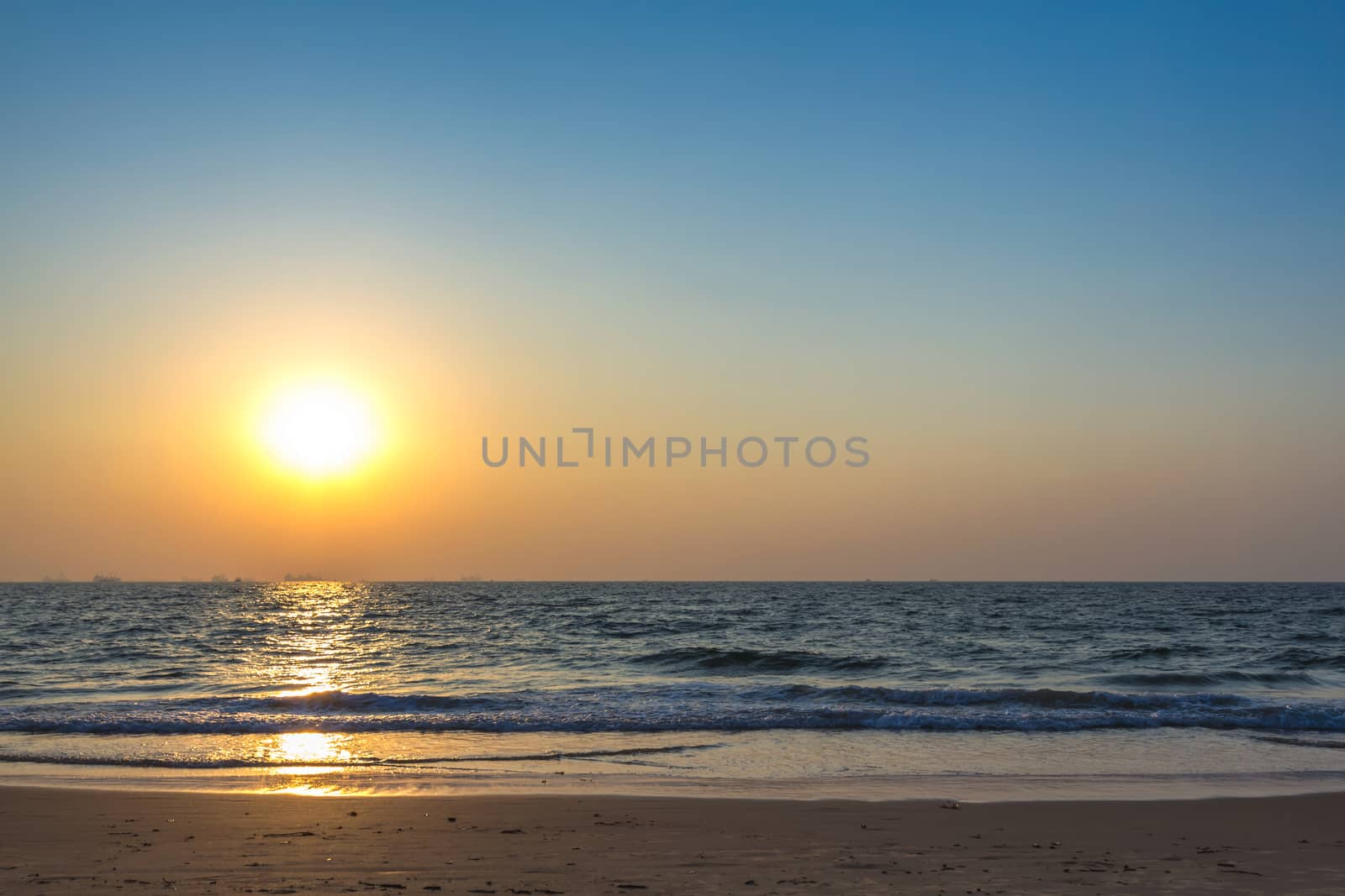 Scenic view from sand beach in Goa to beautiful sunset above the Arabian sea. Sun reflection on sea surface