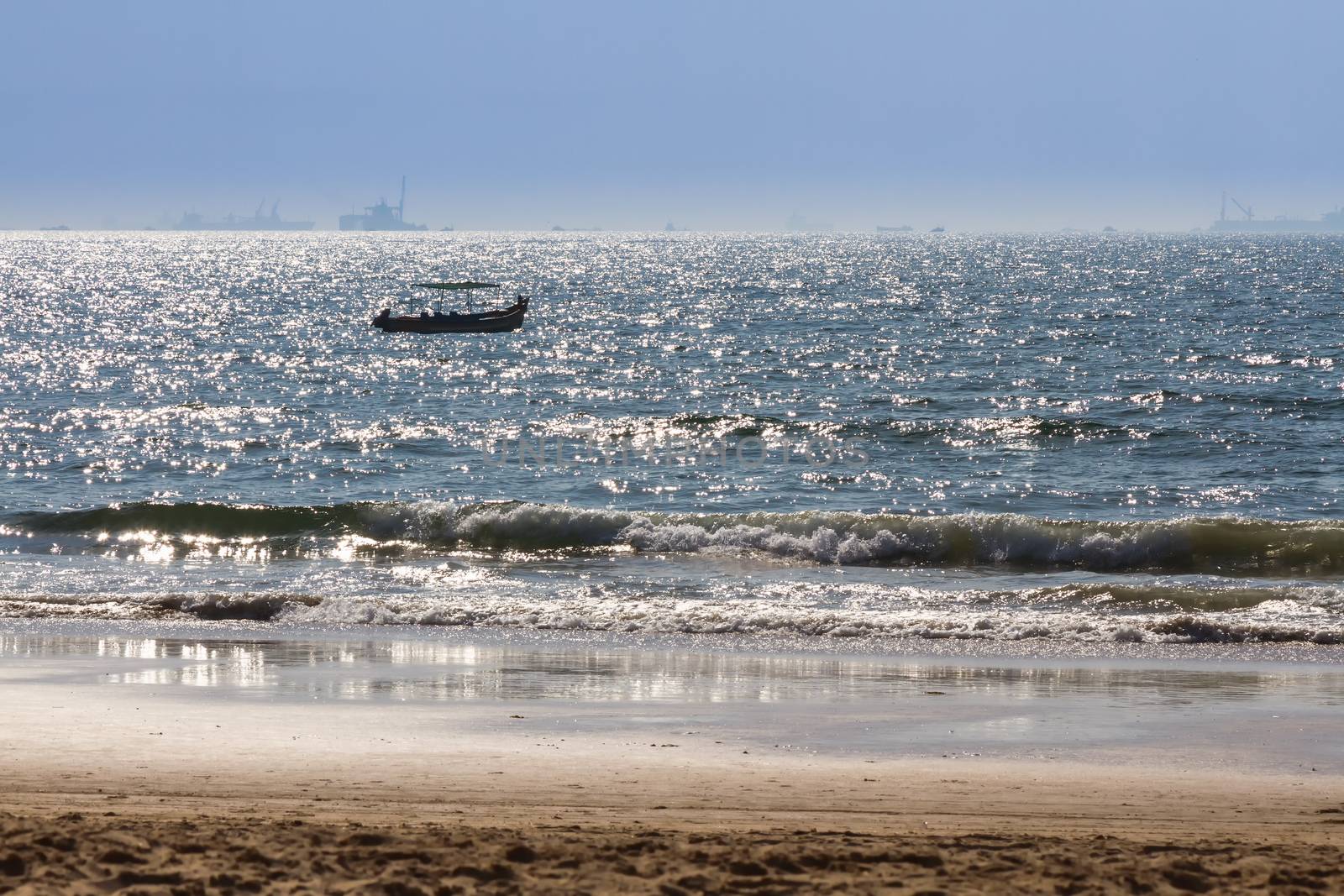 Boats at Arabian sea. Cargo ships on the background. View from beach in Goa, India