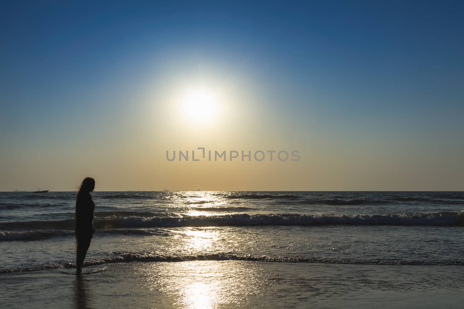Scenic view from beach in Goa to beautiful sunrise above the Arabian sea. Silhouette of woman or girl looks at sea