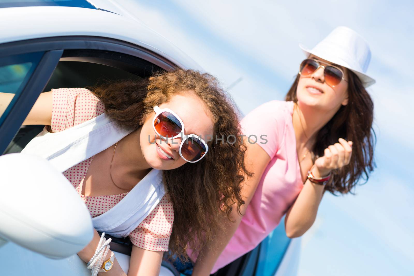 young attractive woman in sunglasses got out of the car window and laugh