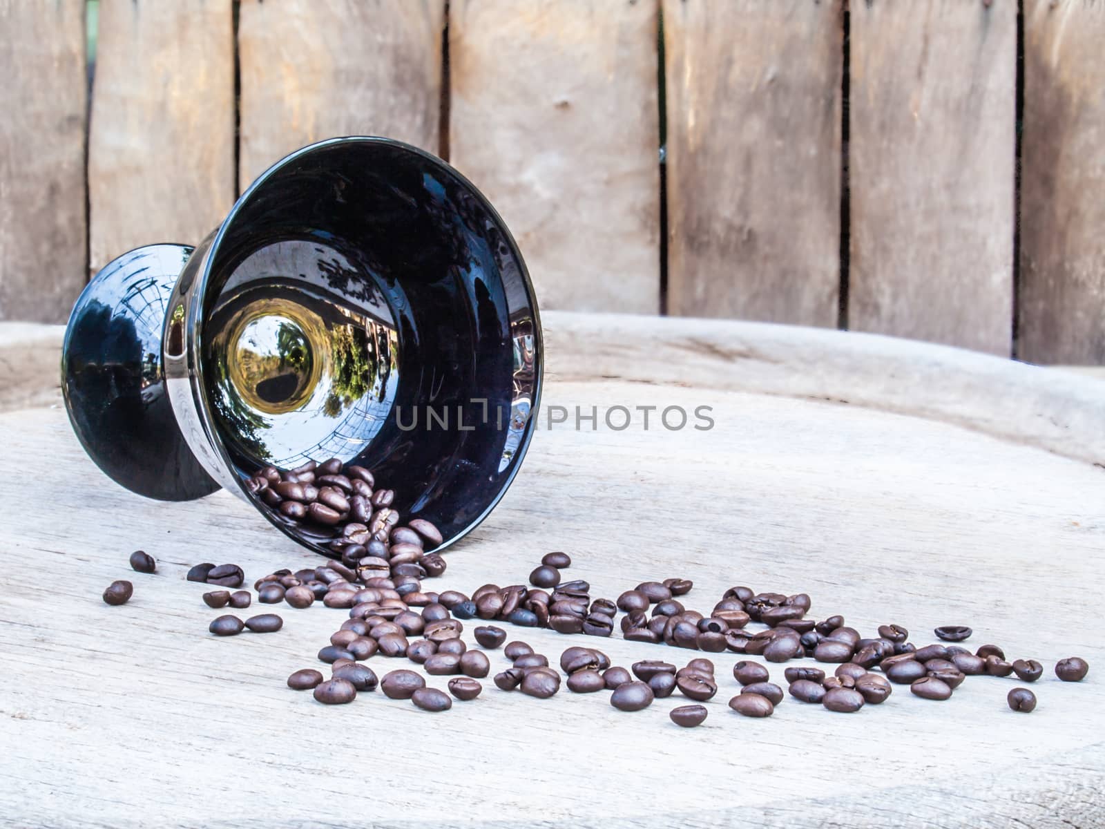 Coffee beans in black bowl on wood background