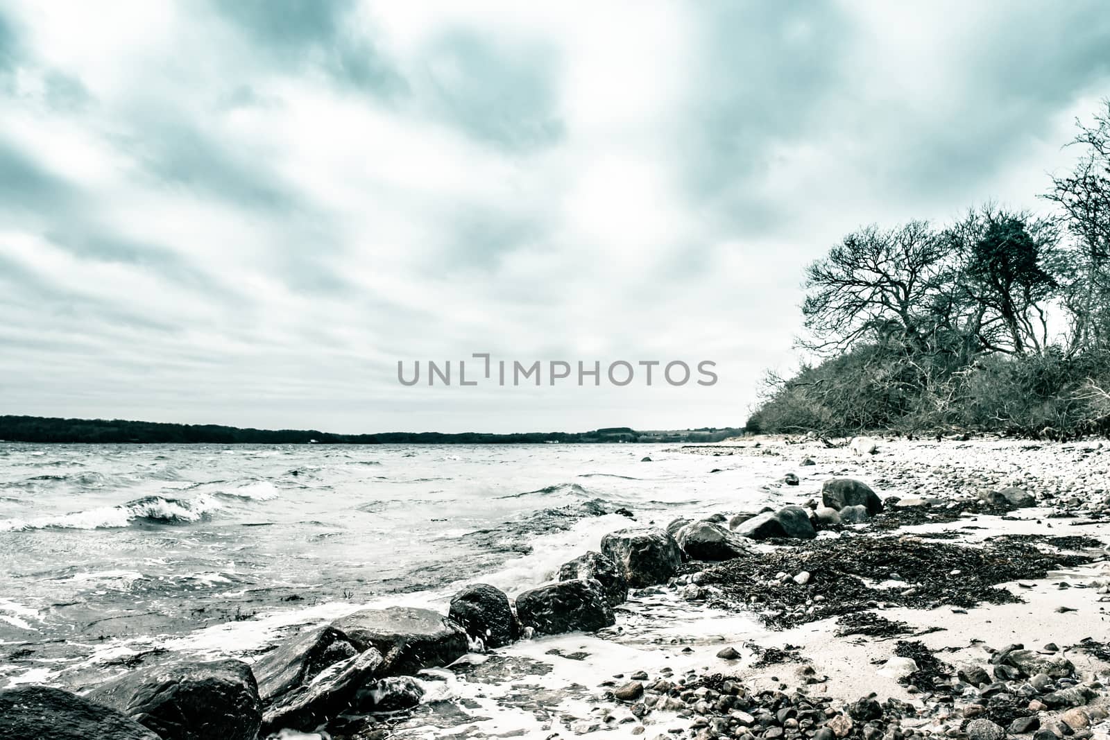 Waves coming in at big black rocks on the shore on a cold day by Sportactive