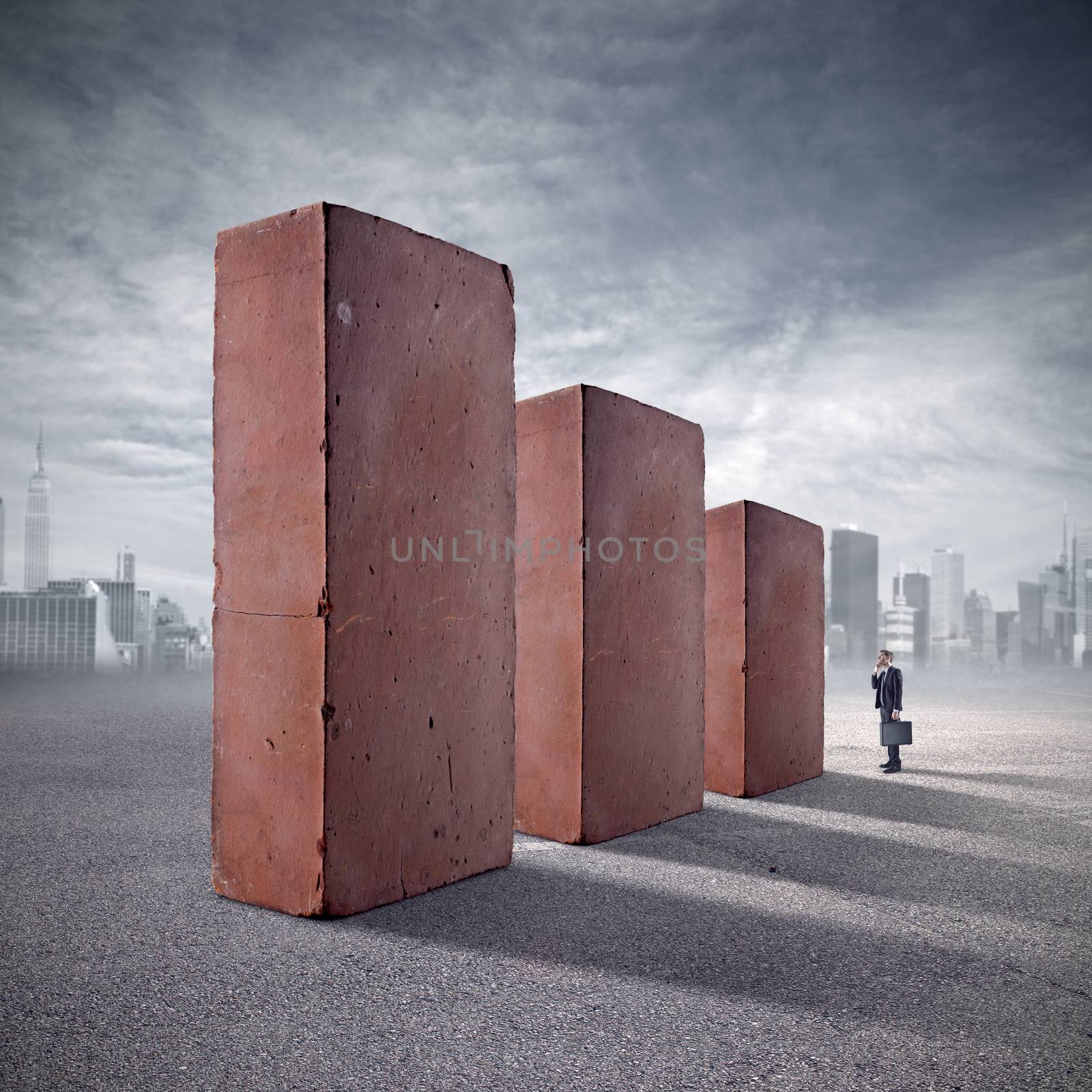 Businessman staring at huge standing bricks with skyline and clouds on background.