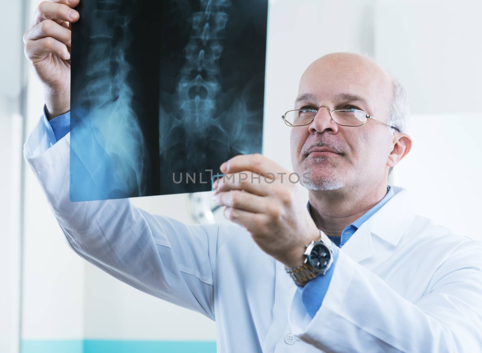 Male senior doctor looking at x-ray images of human spine.