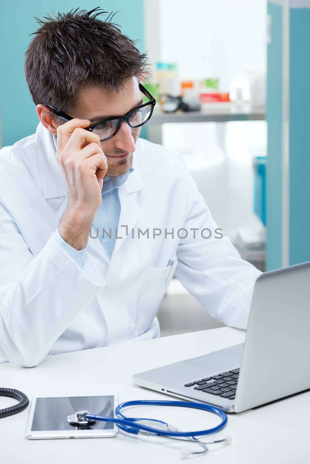 Doctor at work thinking and looking at his laptop.