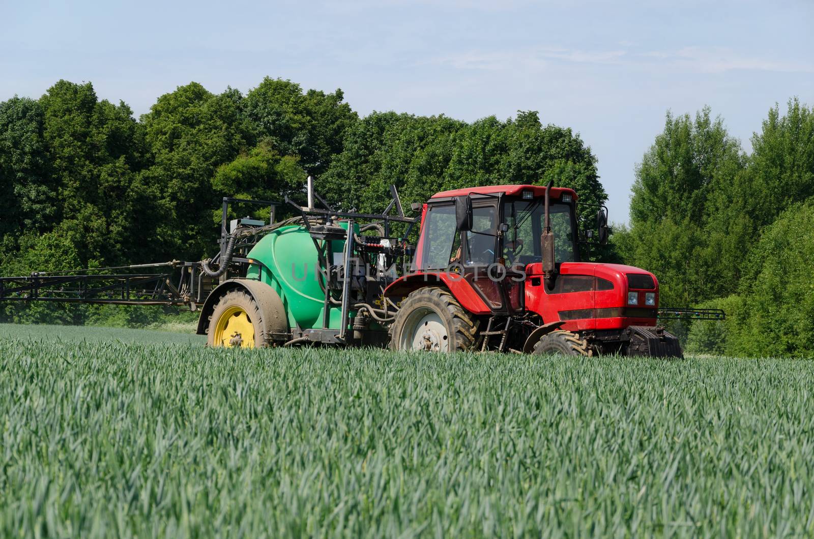 farm machinery tractor long sprayer work in field by sauletas