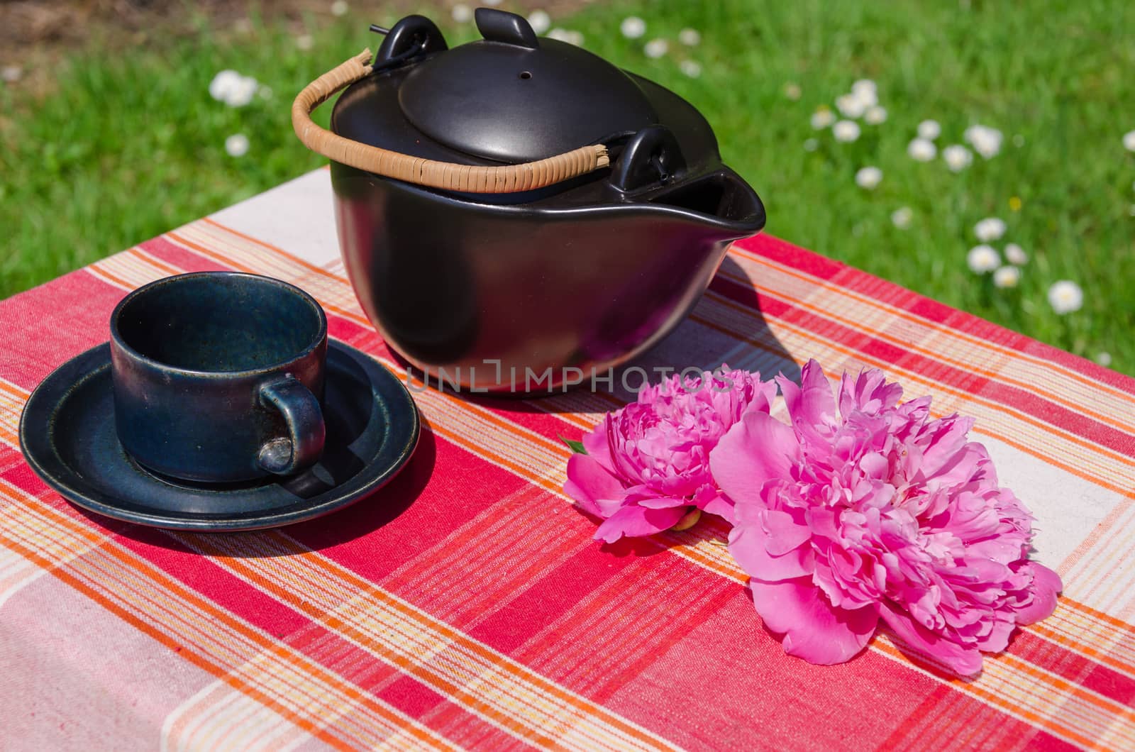 black ceramic teapot and cup with peony on table by sauletas