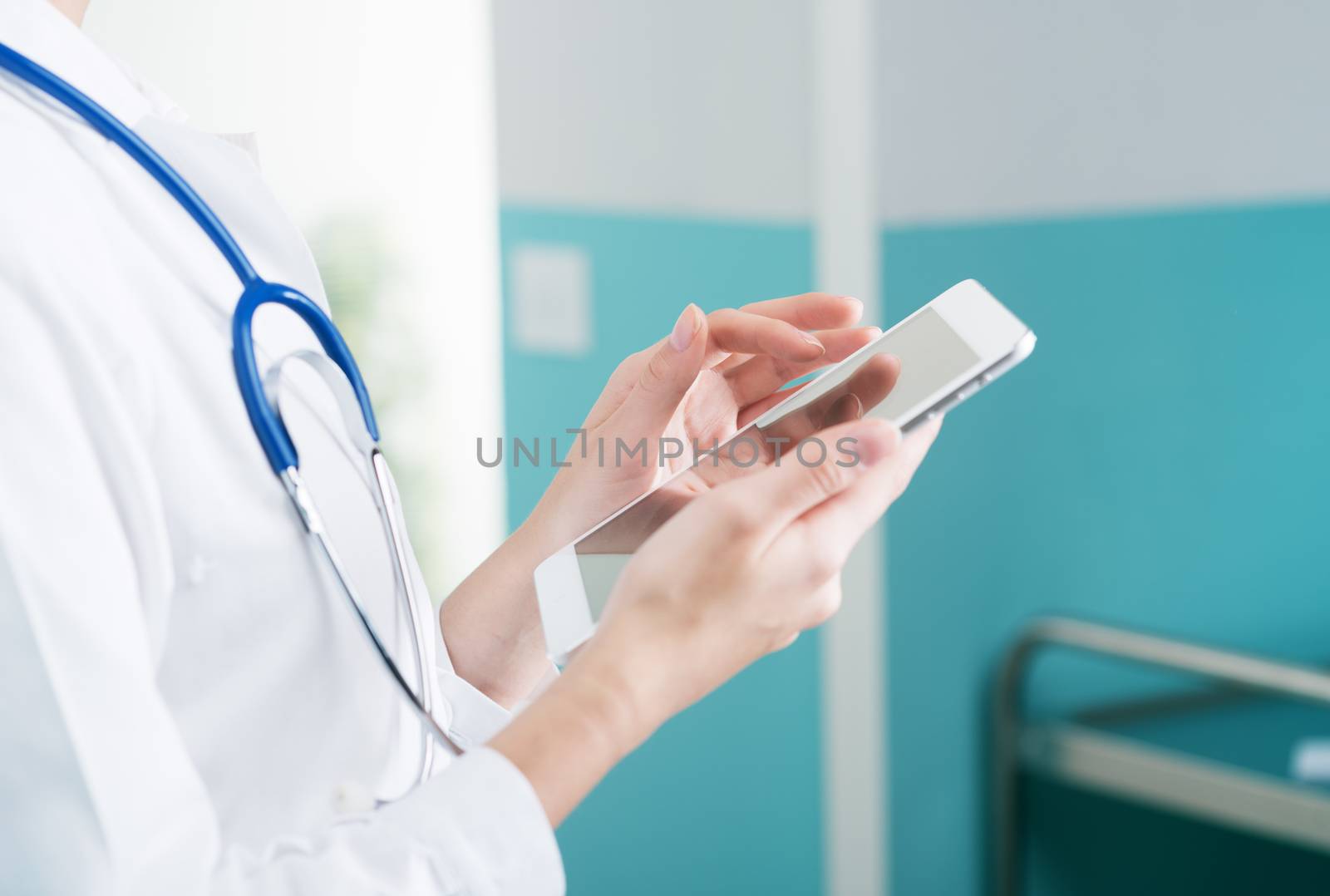 Close up of a female doctor in scrubs using digital tablet.