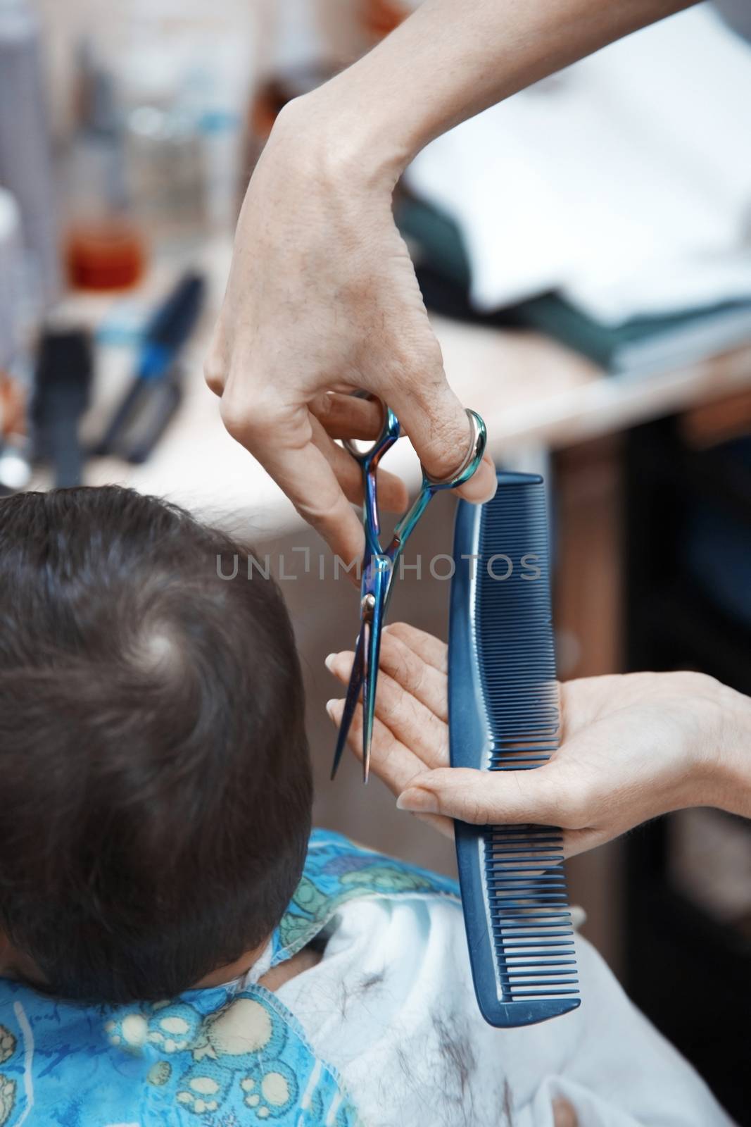 Hands of hairdresser combing baby hair