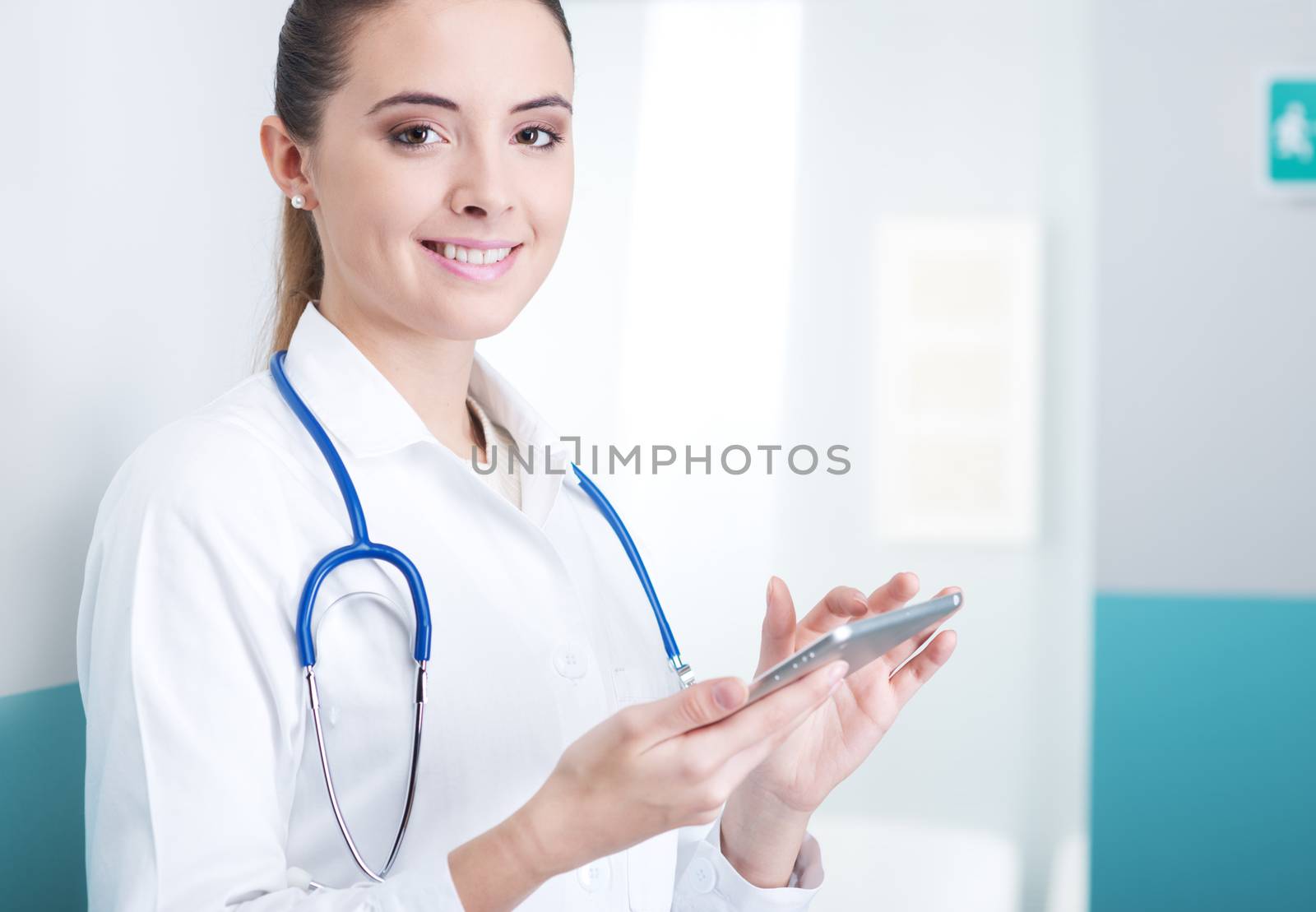 Portrait of a beautiful young female doctor in scrubs with stethoscope around neck using digital tablet.