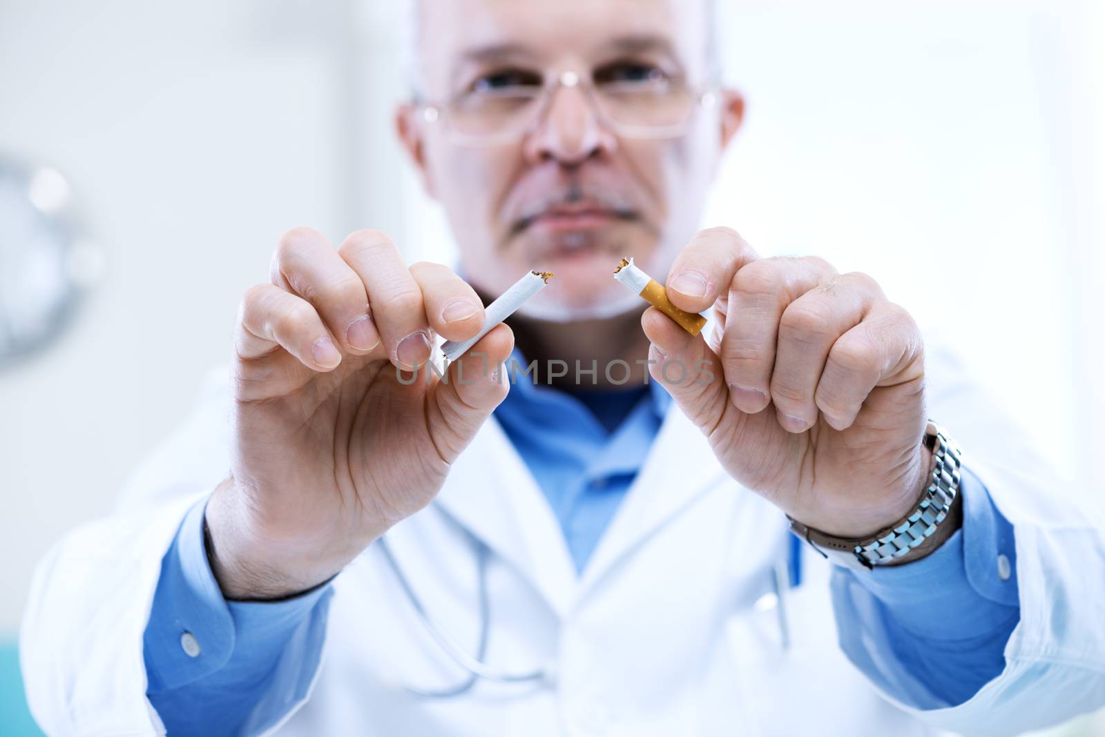 Senior doctor breaking a cigarette, stop smoking concept.