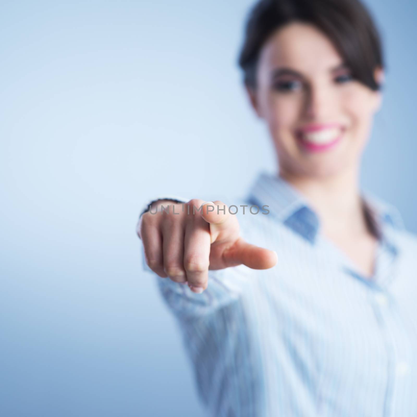 Beautiful young woman smiling and pointing at camera.