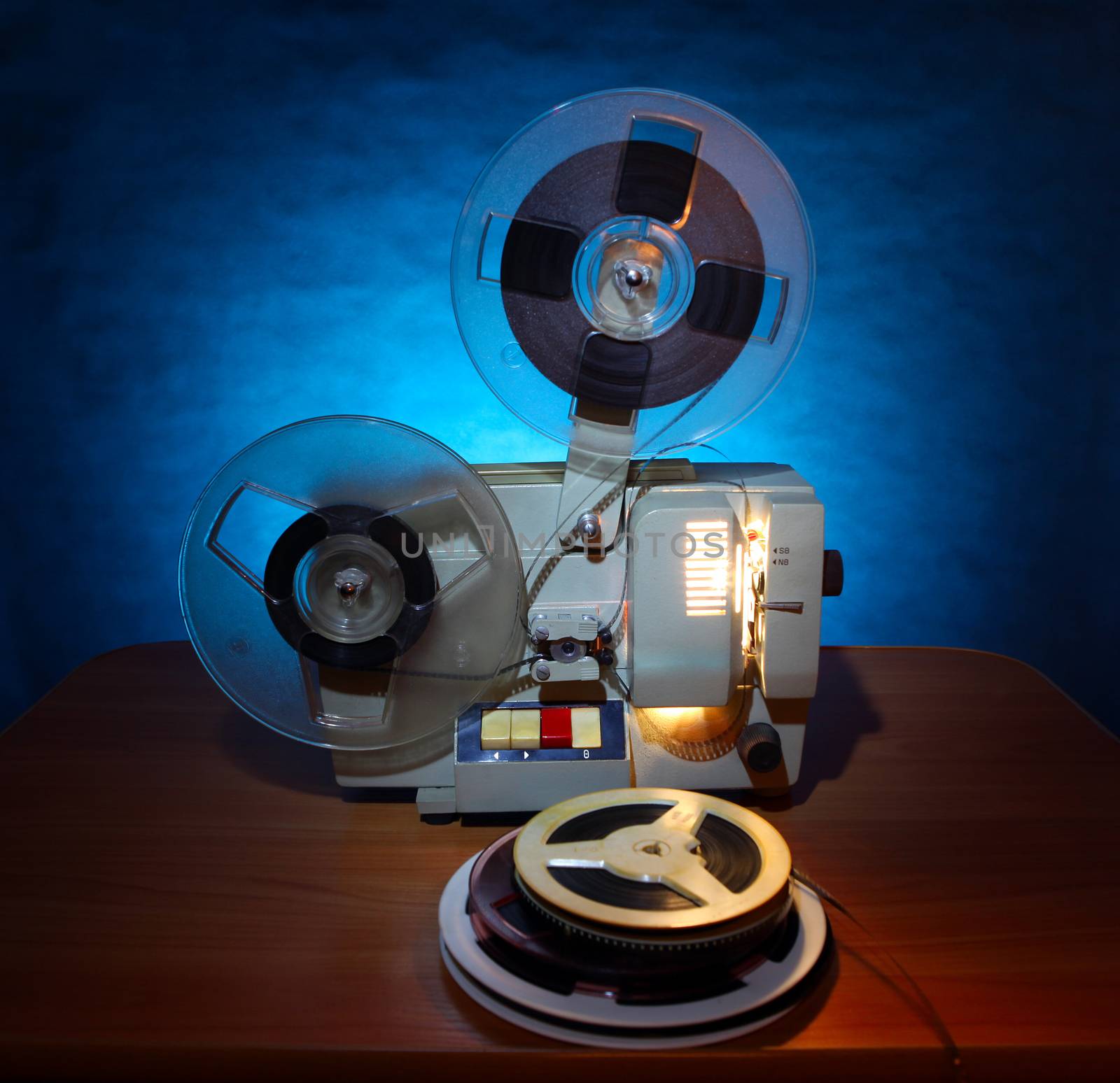 Old 8mm film projector in dusk beside a stack of film reels