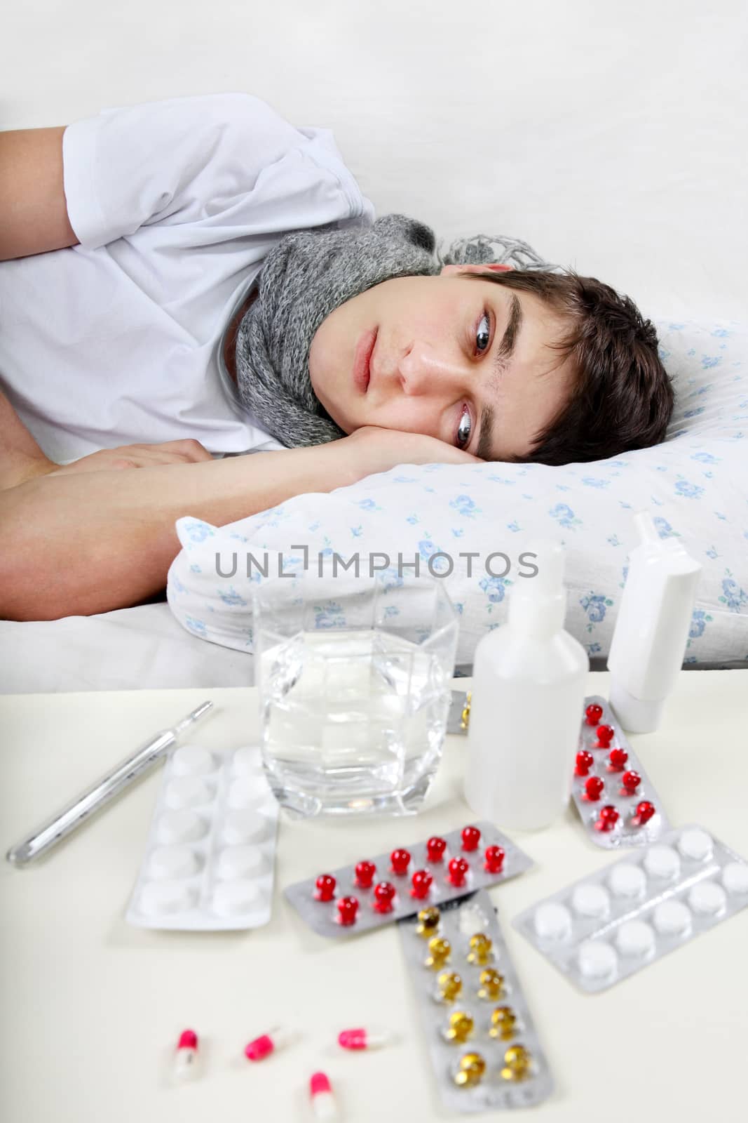 Sick Teenager lying on the Bed with a Pills on foreground