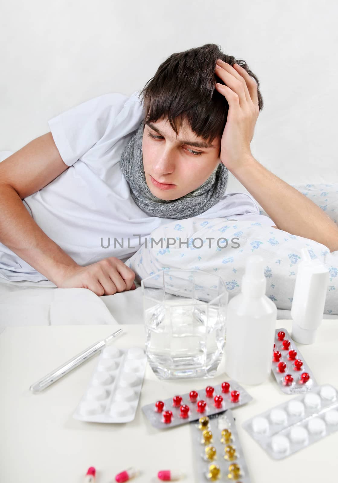 Sick Teenager lying on the Bed with a Pills on foreground