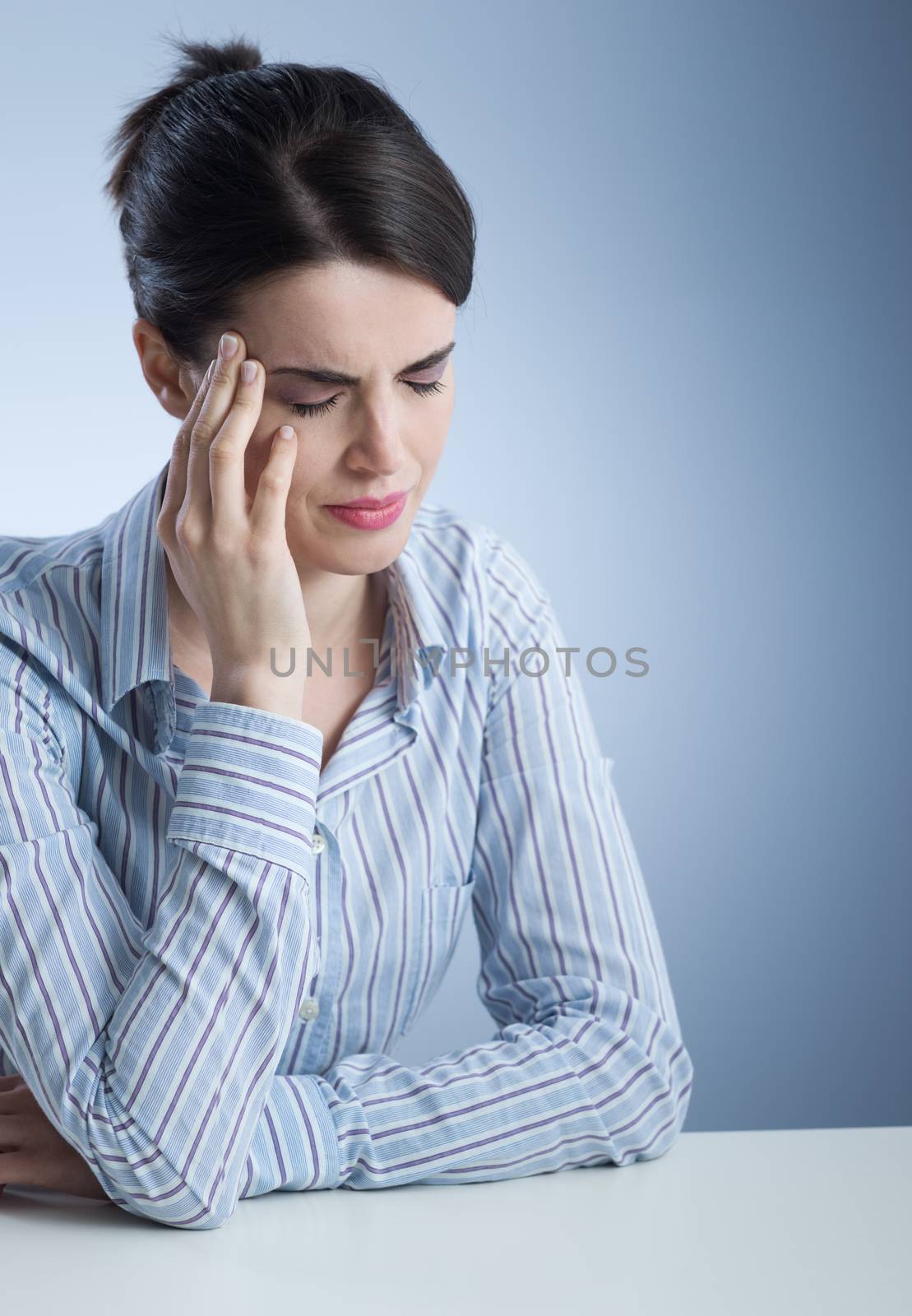 Young woman with headache touching her temples.