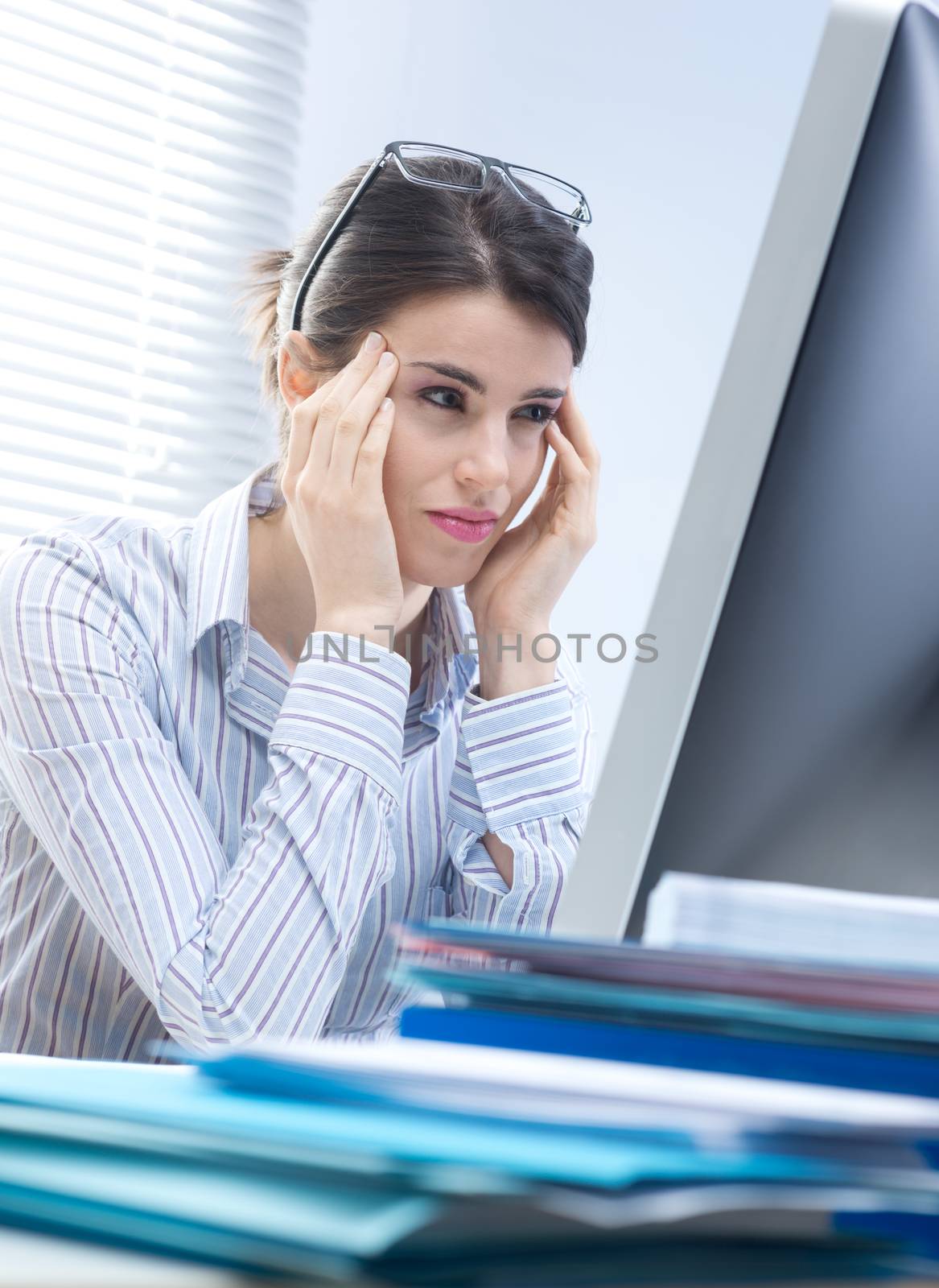 Tired businesswoman with headache touching her temples at desk.