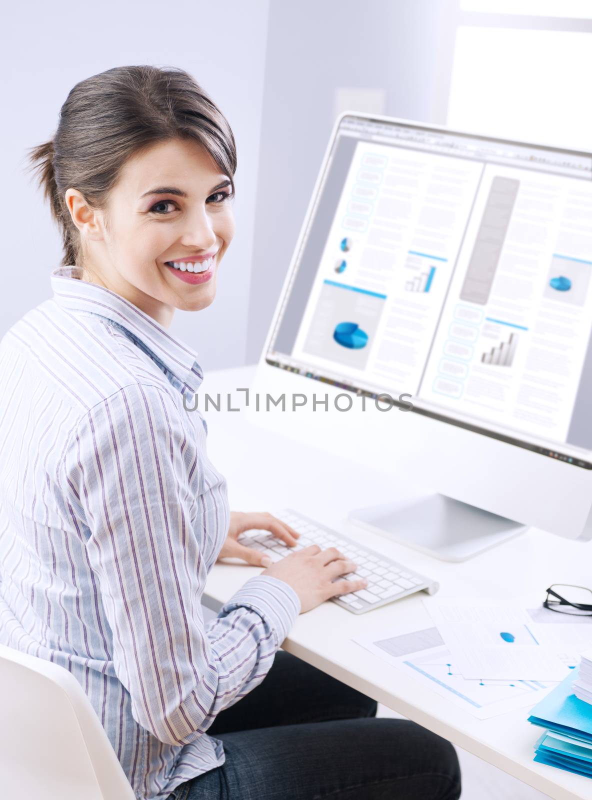 Young office worker smiling and typing on a  keyboard at office.