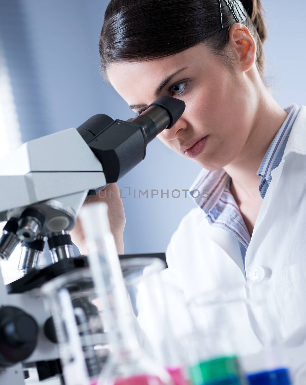 Female researcher using microscope by stokkete