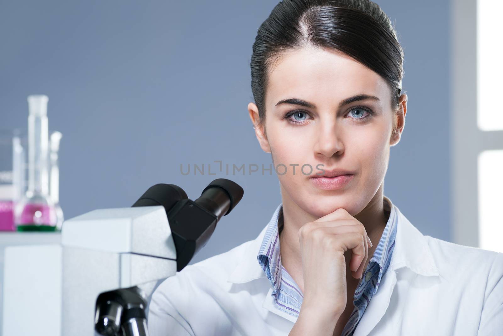 Confident female researcher in the chemistry lab with equipment on background.