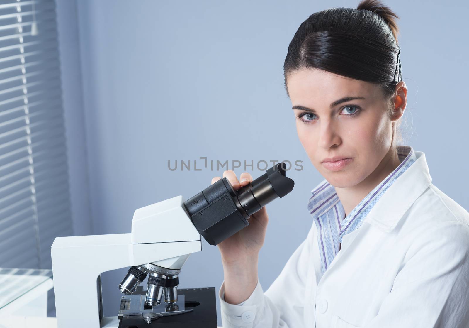 Female researcher working with microscope by stokkete