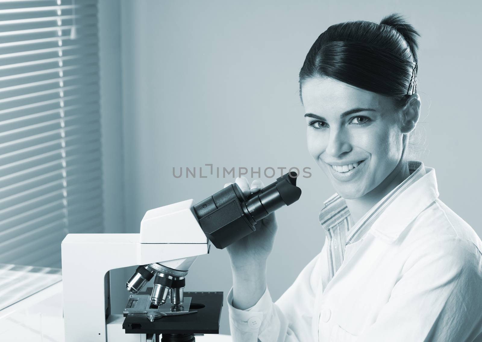 Female researcher working with microscope by stokkete