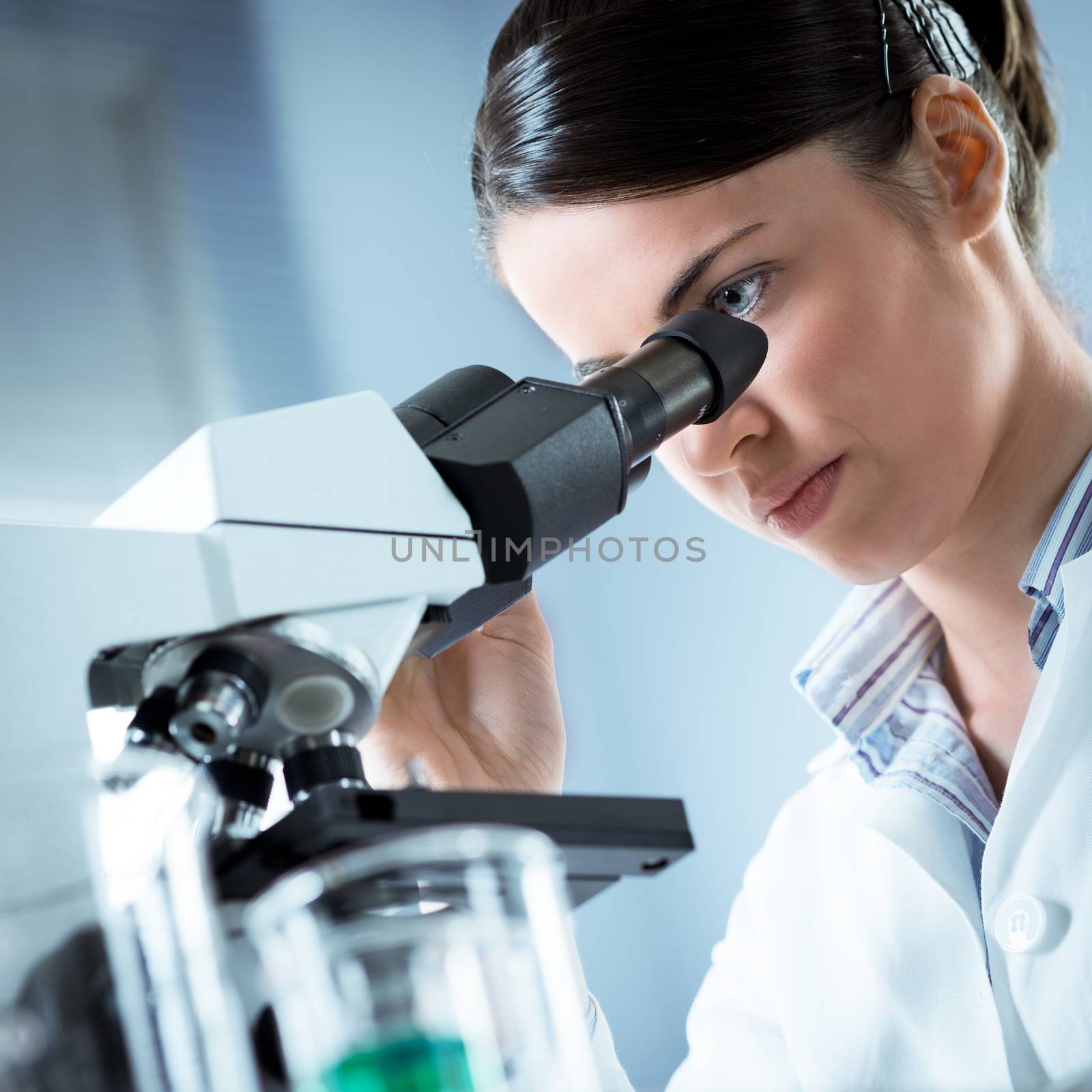 Female researcher analyzing samples with microscope in the laboratory.