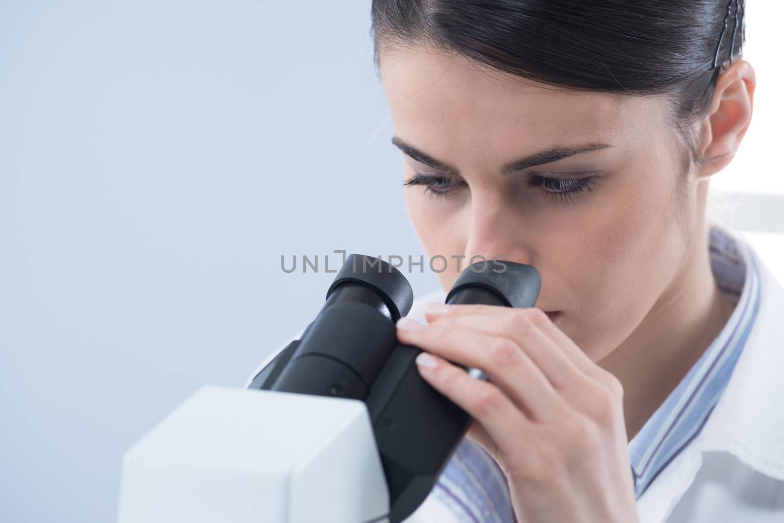 Young female researcher using microscope in the laboratory close up.