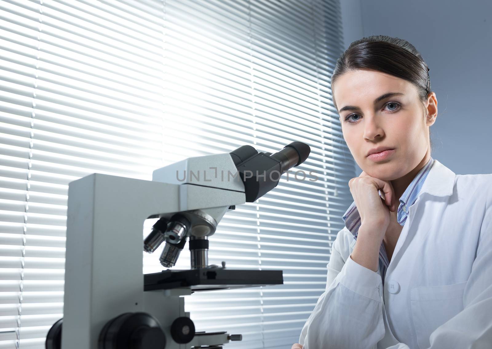 Female researcher working with microscope by stokkete