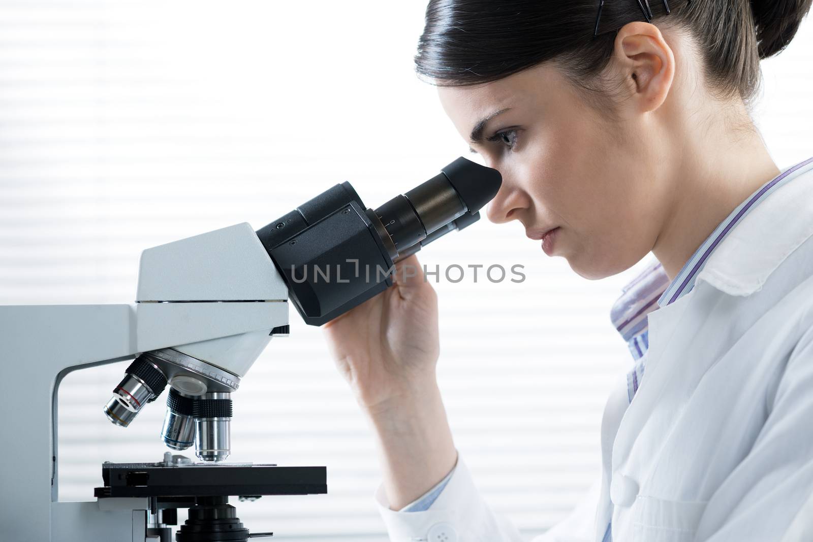 Female researcher using microscope by stokkete