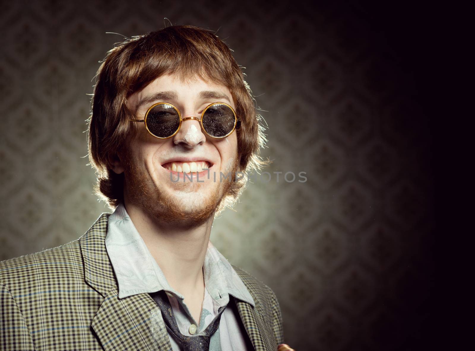 Funny 1960s style guy after snorting cocaine on vintage wallpaper background.