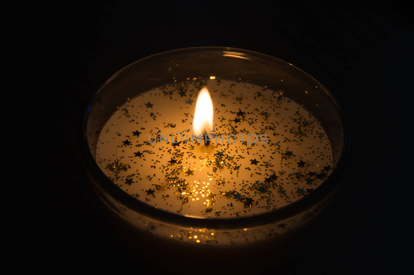 candle with gold stars in the dark