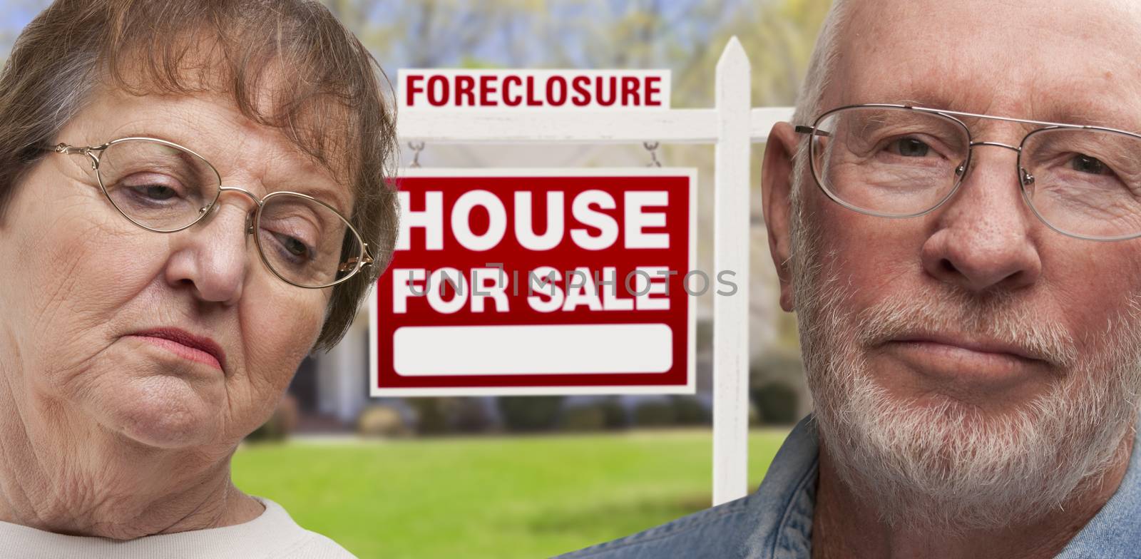 Depressed Senior Couple in Front of Foreclosure Real Estate Sign and House.