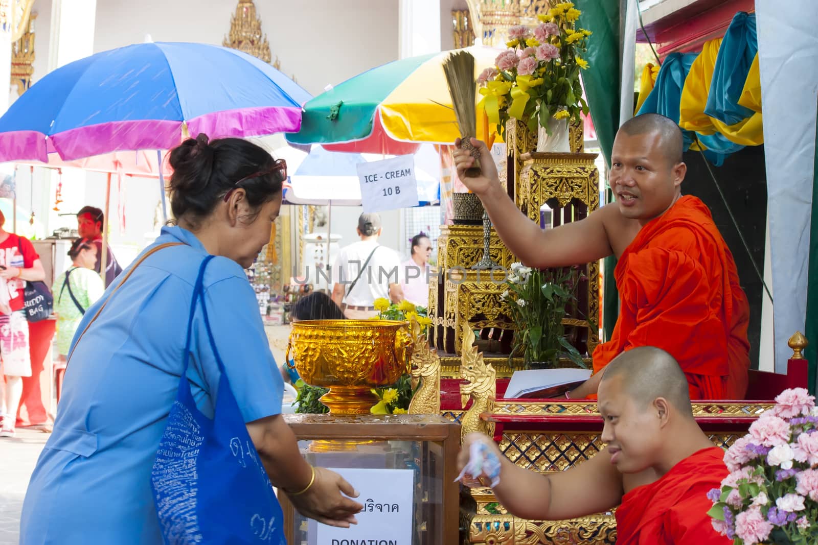 Unidentified monk pouring a holy water to people for a good luck in Songkran festival tradition of thailand. Photo: Amnarj2006/ yaymicro.com