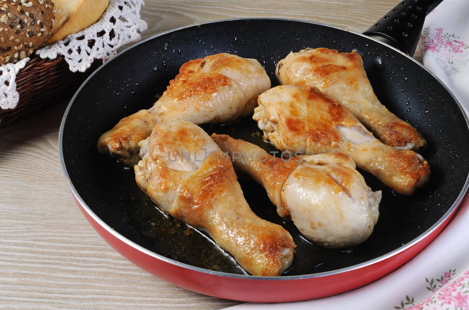 Ruddy fried chicken drumsticks in pan closeup