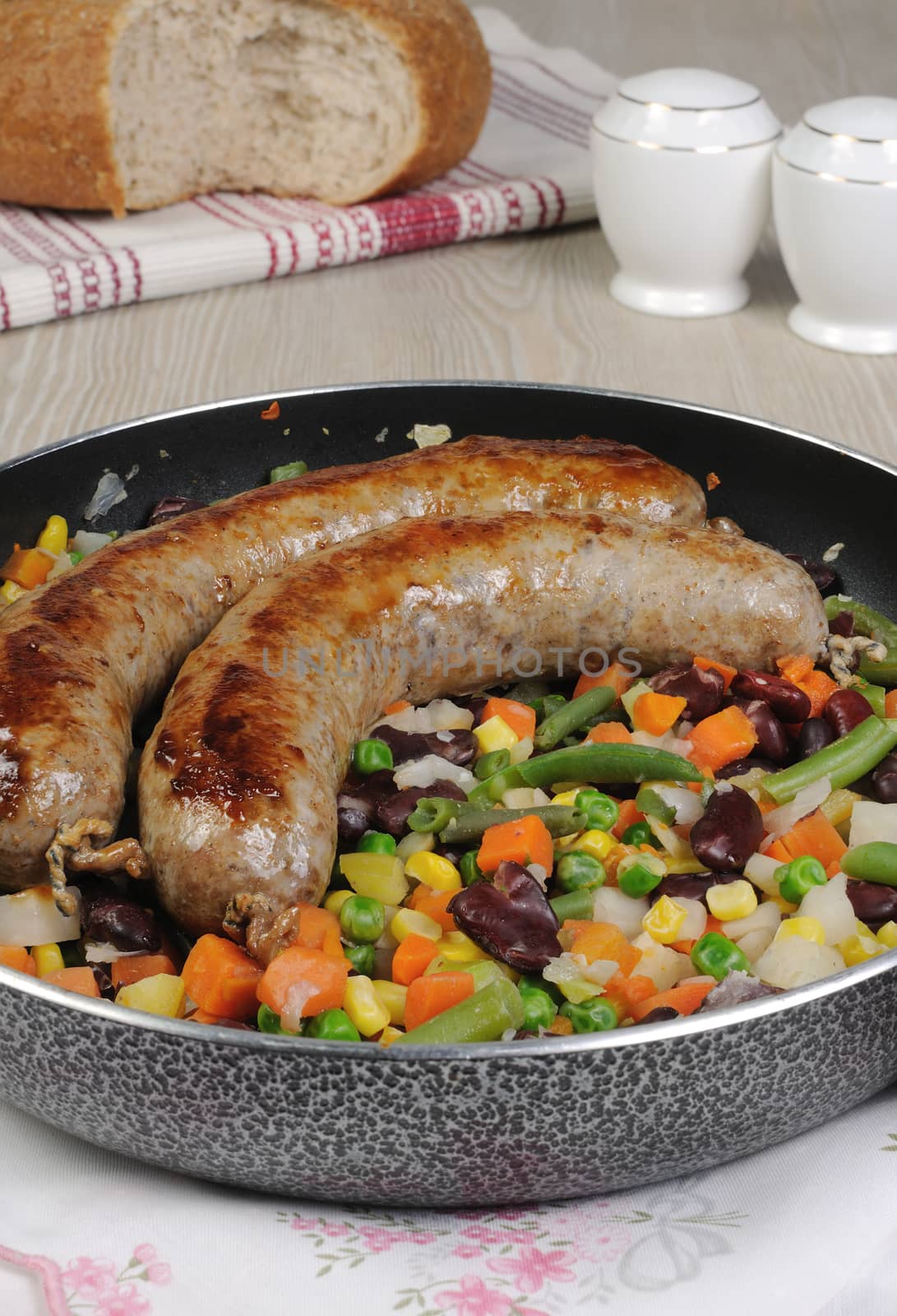 Homemade sausages with vegetables in a pan