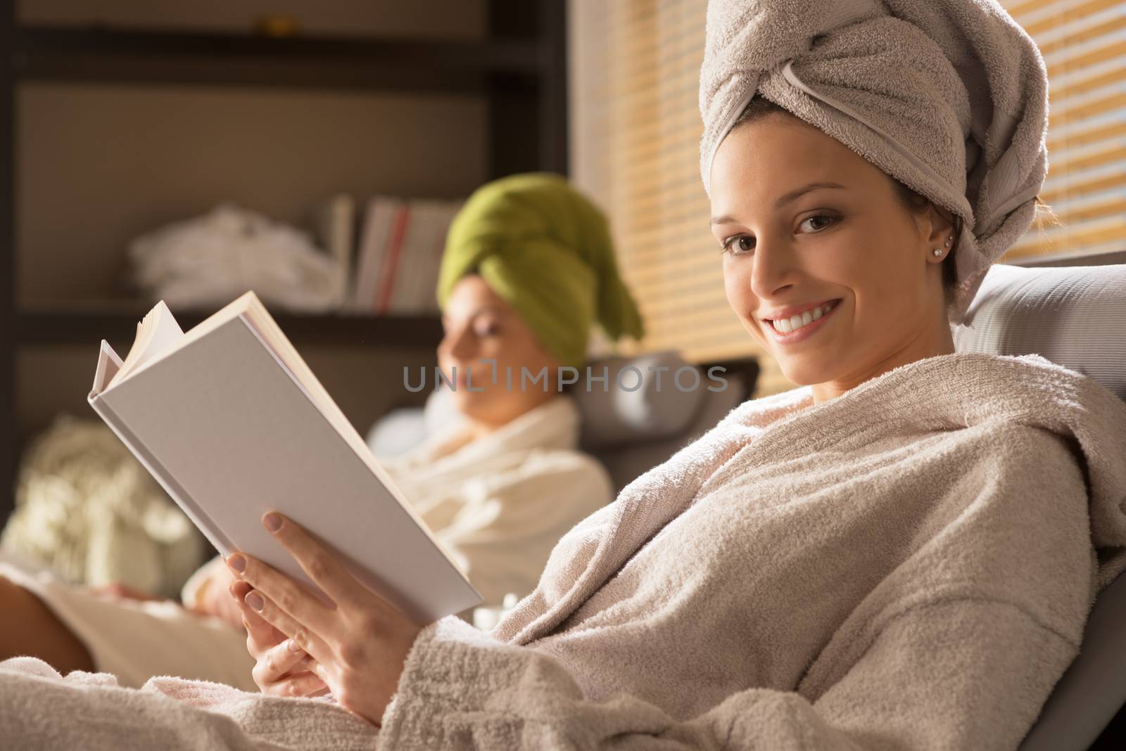 Beautiful woman relaxing at spa lying on sofa and reading.