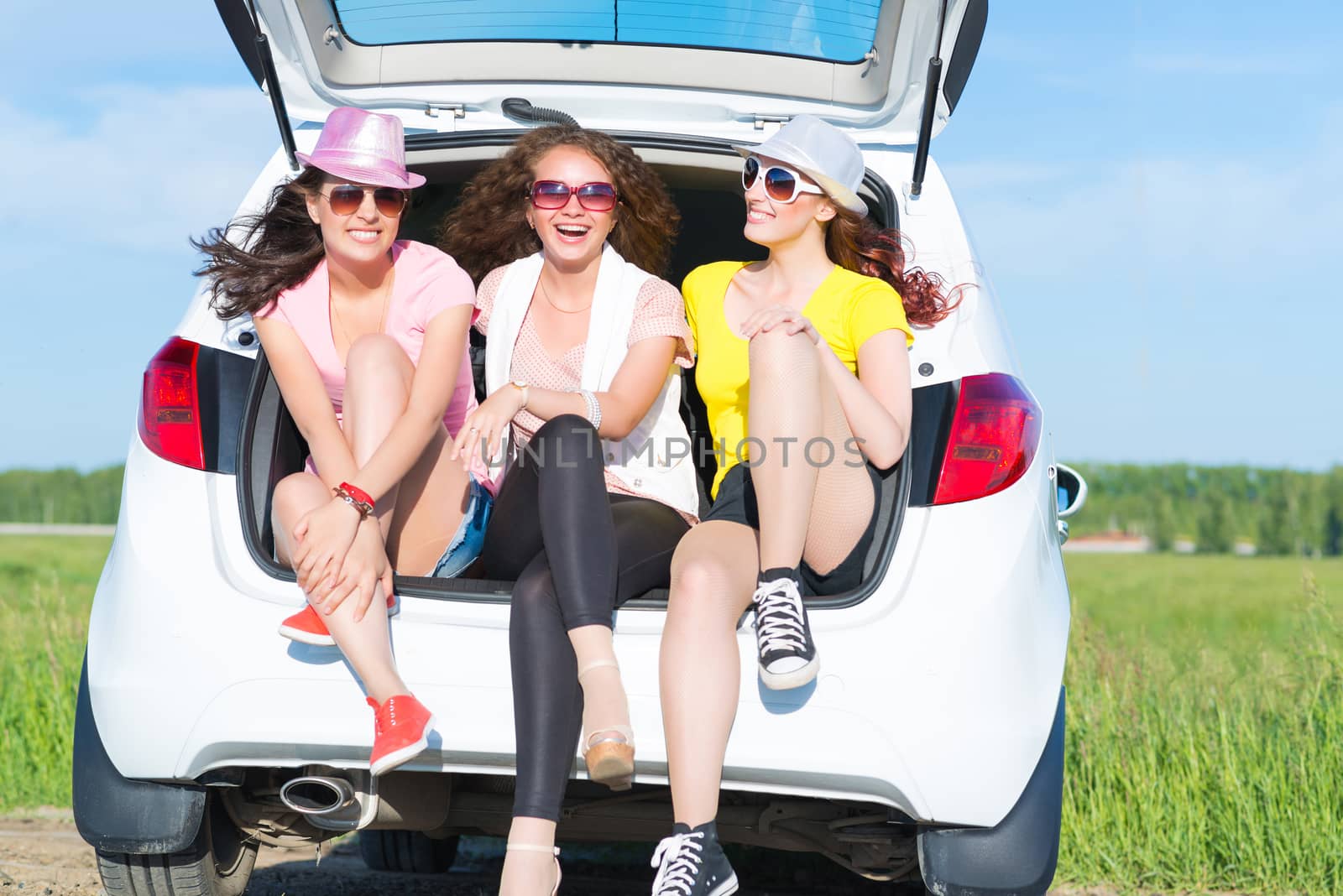 young attractive woman sitting in the open trunk of a new car, a summer road trip