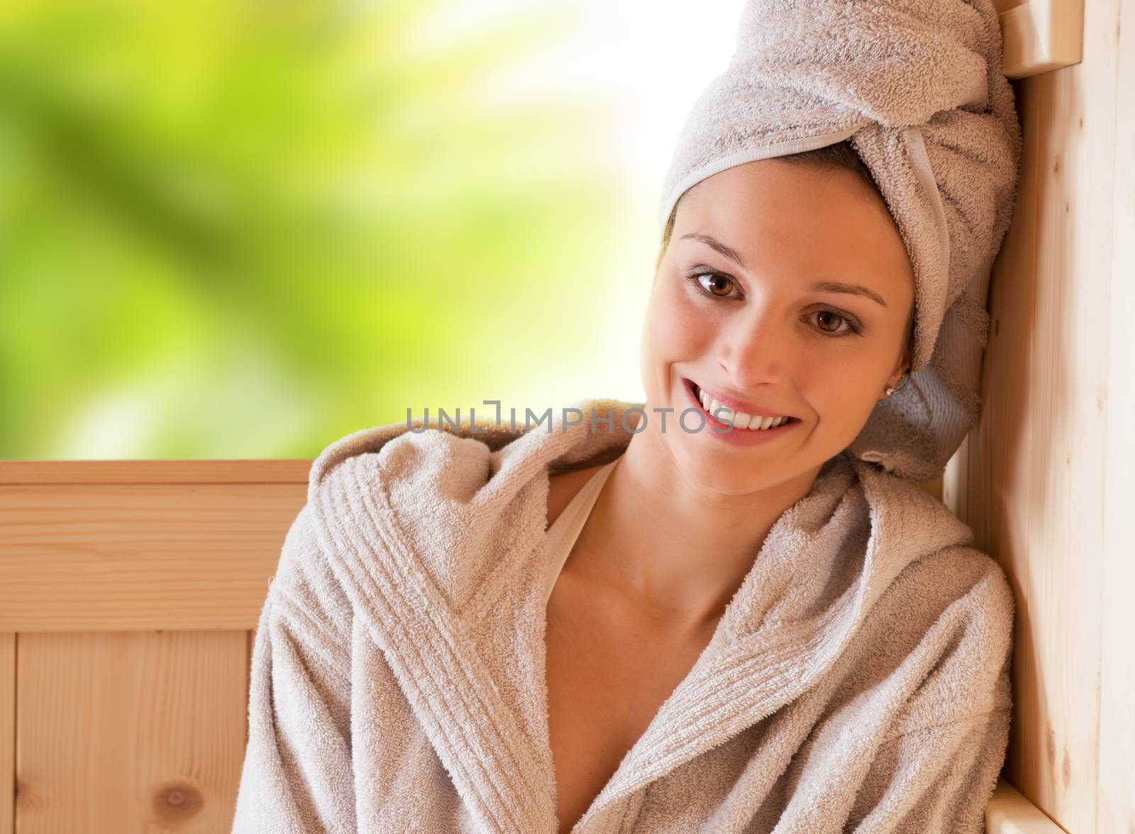 Young attractive woman smiling and relaxing in sauna at spa.