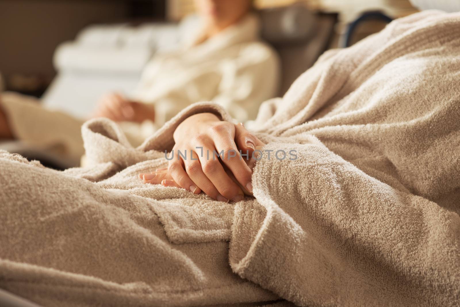 Women in bathrobe relaxing at spa, lying on a sofa.