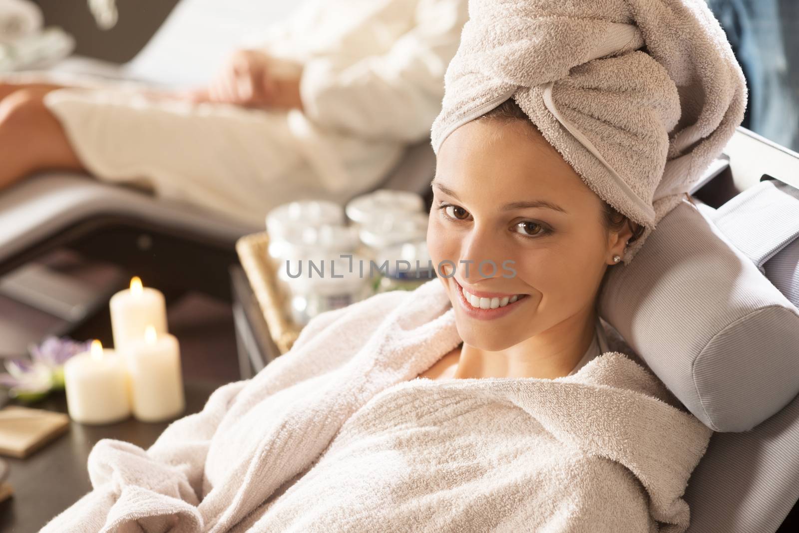 Beautiful woman enjoying spa treatments with candles on background.