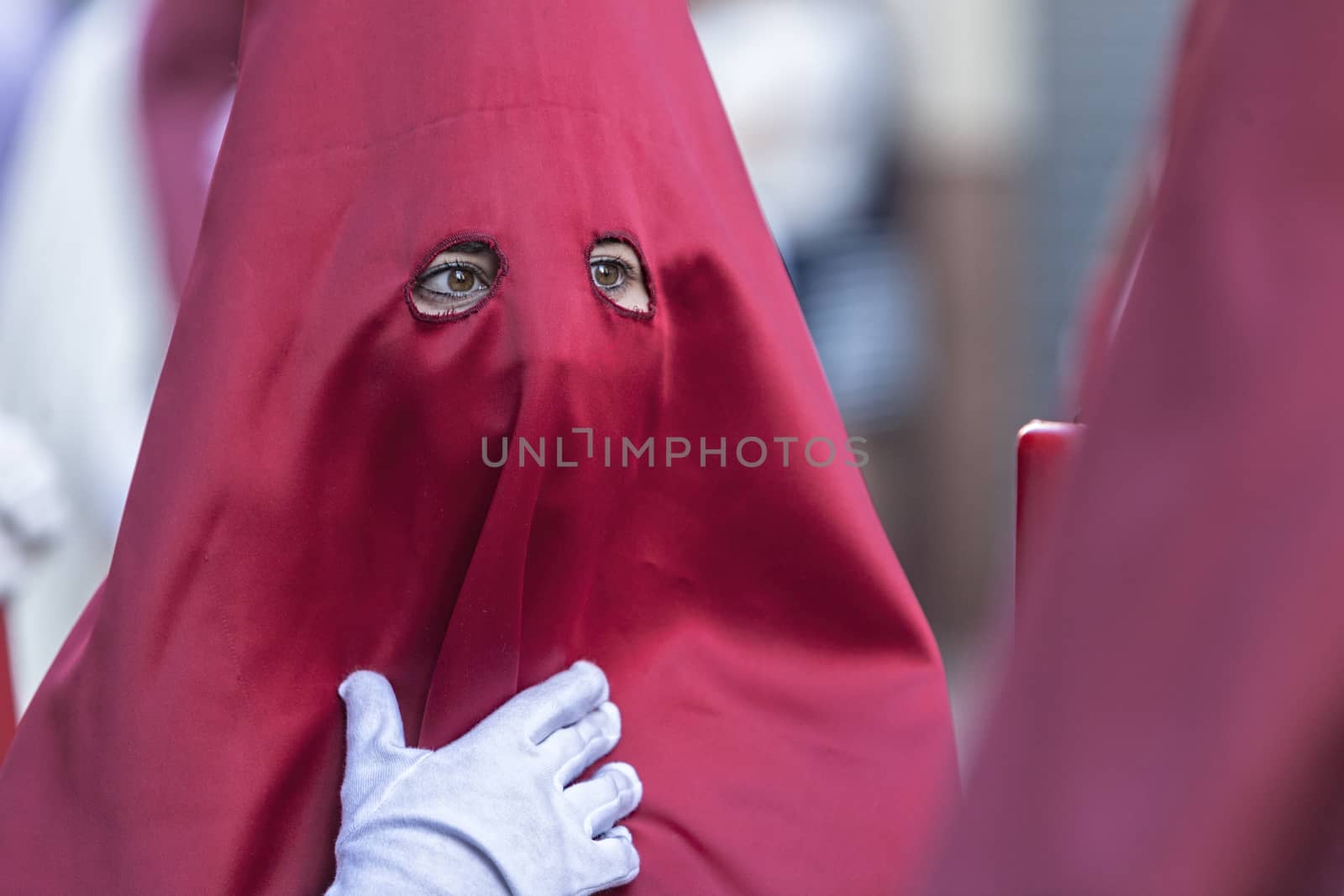 Detail penitent red holding a candle during Holy Week, Spain