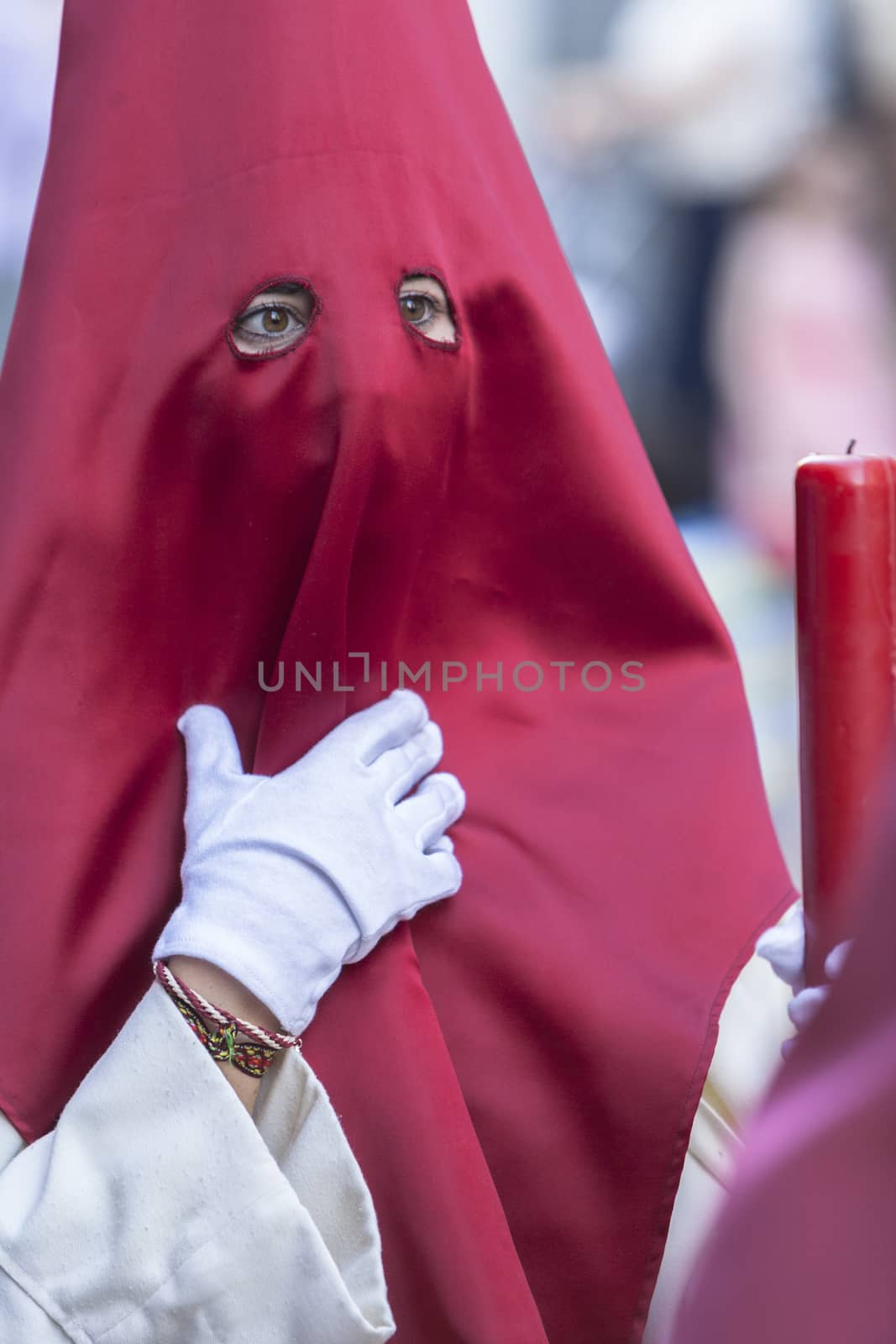 Detail penitent red holding a candle during Holy Week, Spain
