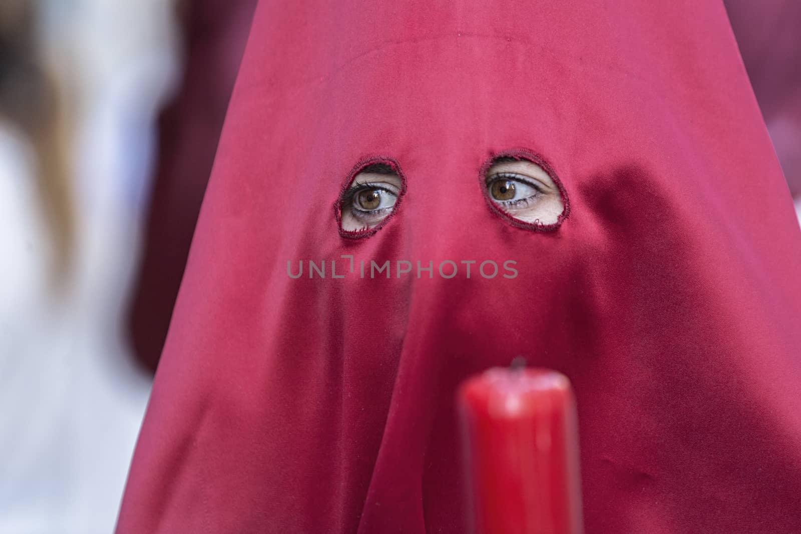 Detail penitent red holding a candle during Holy Week, Spain