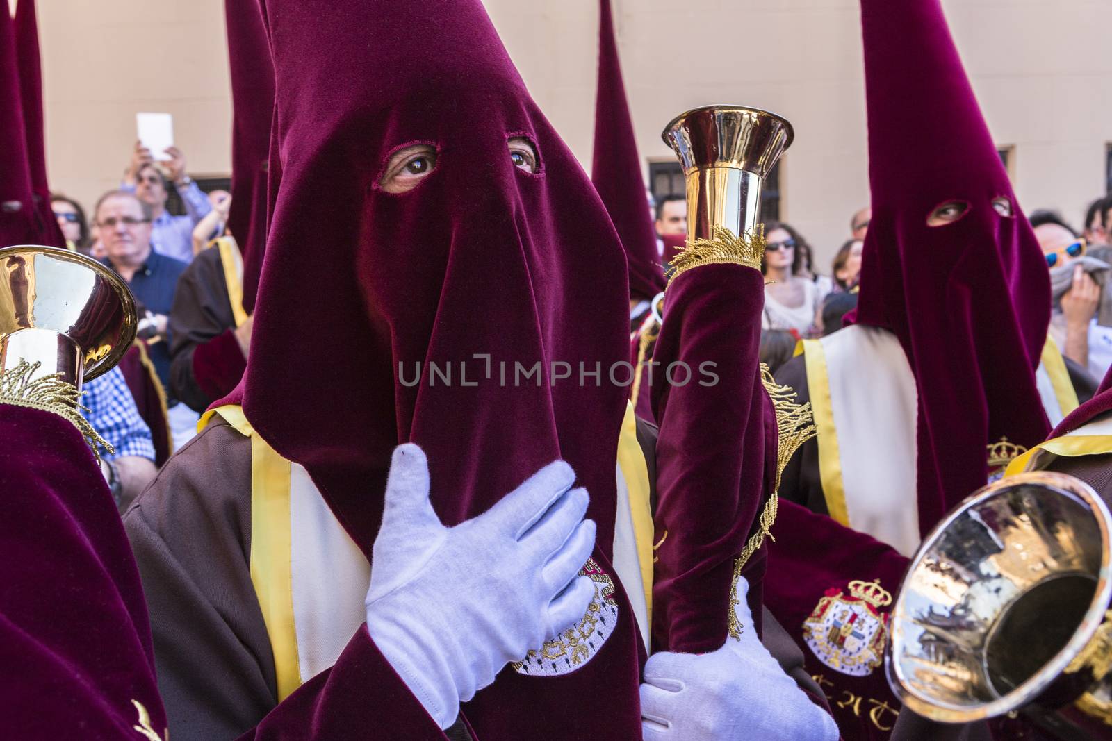Linares, Jaen province, SPAIN - March 17, 2014: Nazarenes with red tunics and trumpets in the hands of penance during station, taken in Linares, Jaen province, Andalusia, Spain